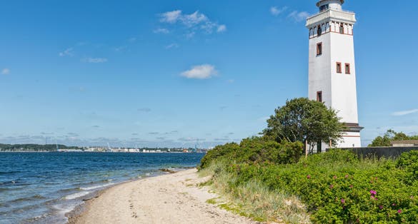 photo of view of Lighthouse at the beach of Strib, Middelfart, Denmark. harbor of Fredericia in background, Middelfart, Denmark.