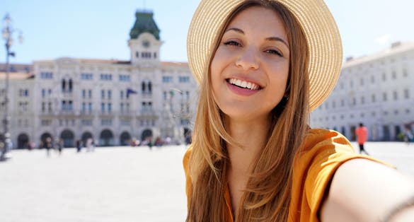 photo of cultural tourism in Italy. Self portrait of smiling traveler girl visiting piazza unità d'Italia Trieste, Italy.