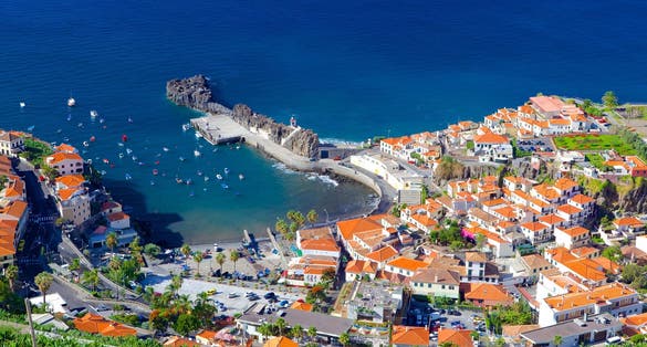 Amazing Madeira island with beautiful fishing Câmara de Lobos village with houses, pier, mountain and ocean