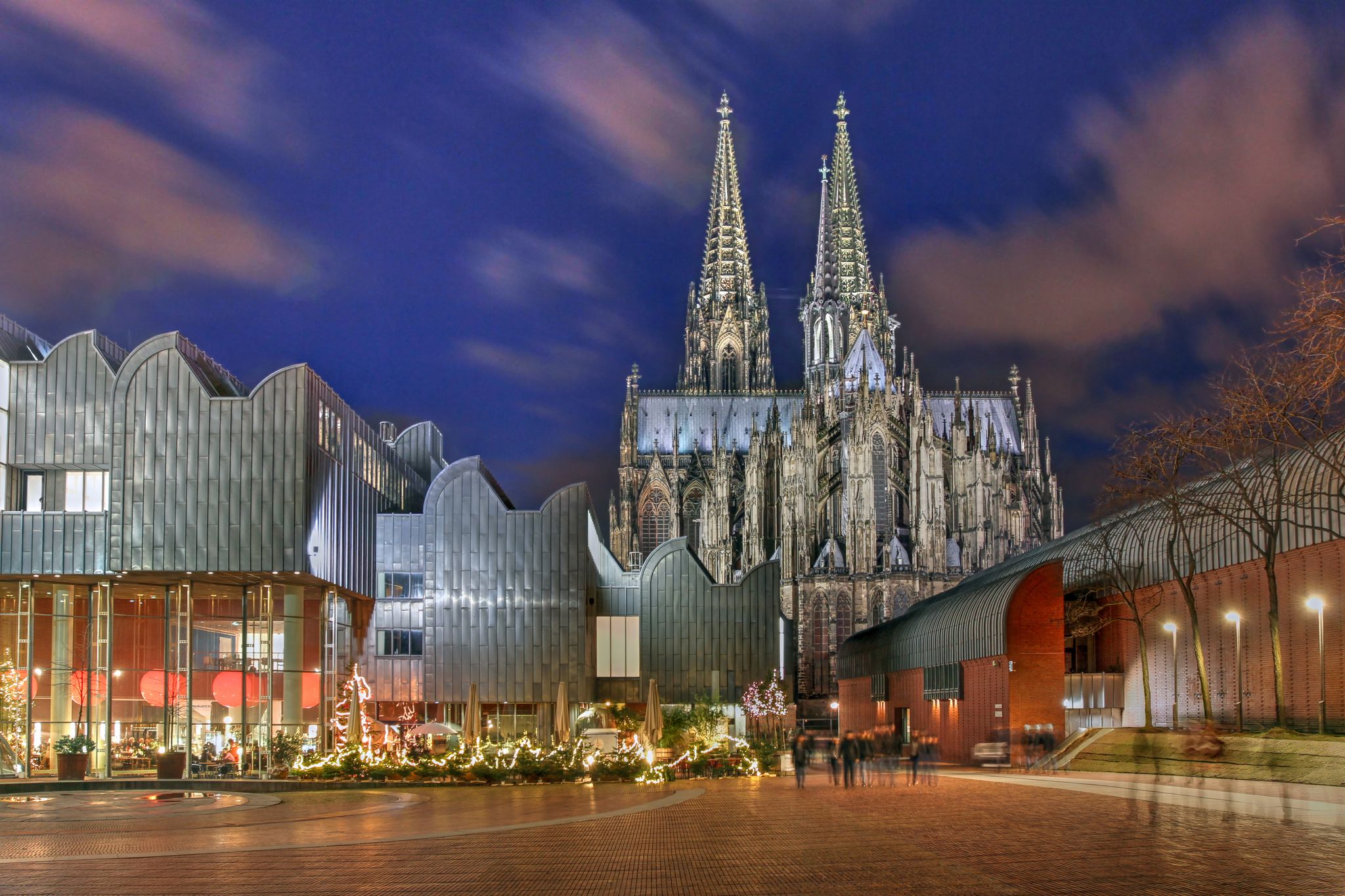 Night scene of Heinrich-Boell square in Cologne, Germany with the Cologne Philarmonie Hall and the Ludwig Museum, overlooked by the majestic Cologne Cathedral.