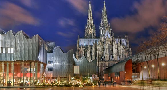 Night scene of Heinrich-Boell square in Cologne, Germany with the Cologne Philarmonie Hall and the Ludwig Museum, overlooked by the majestic Cologne Cathedral.