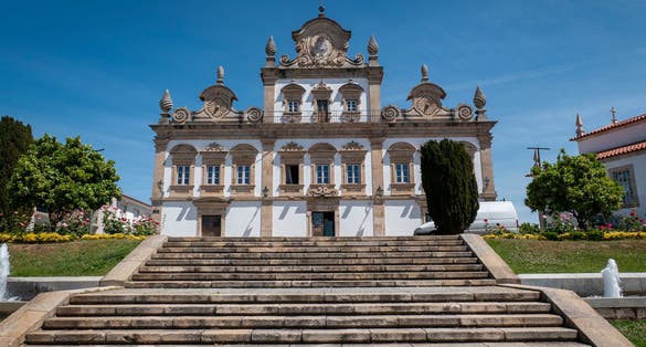 Photo of Mirandela City Hall building and the access stairs to it, surrounded by a beautiful garden and a blue sky in Trás os Montes, Portugal.