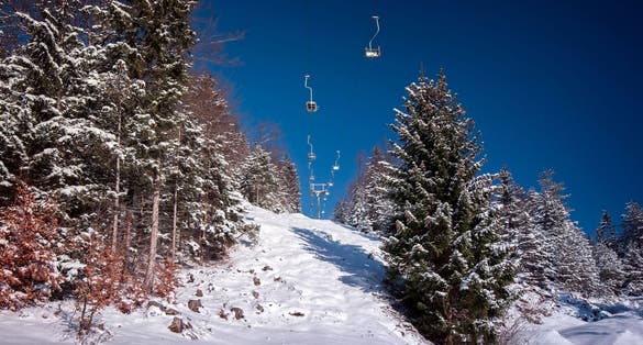 Photo of Winter Mountain landscape with ski lift in snowy forest recreation ski resort area in Bavaria, Germany on sunny day.