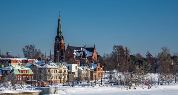 Umea City Church in winter overcast, many old buildings at frozen river coast, blue clear sky, Sweden.
