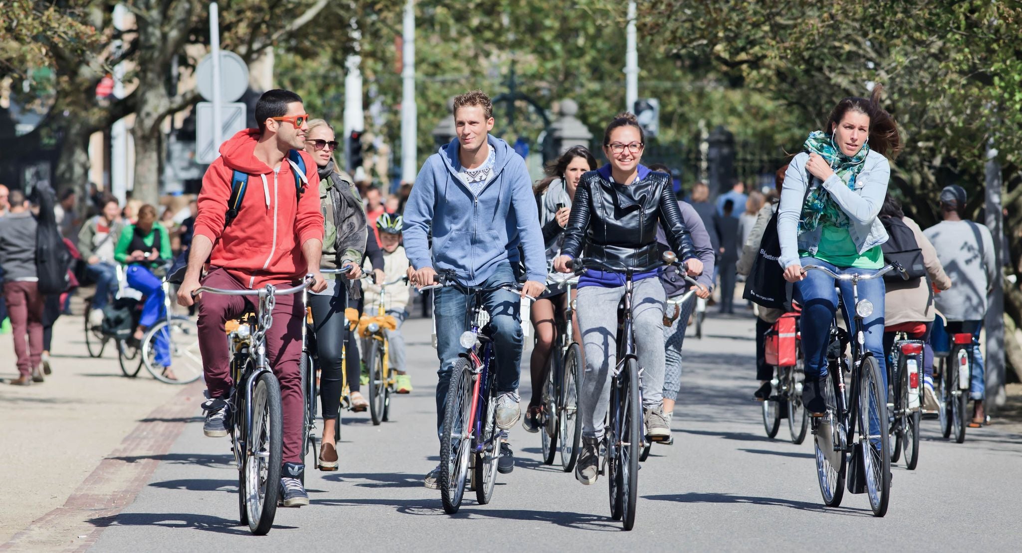 Group of people cycling through a sunny street in Amsterdam during summer..jpg