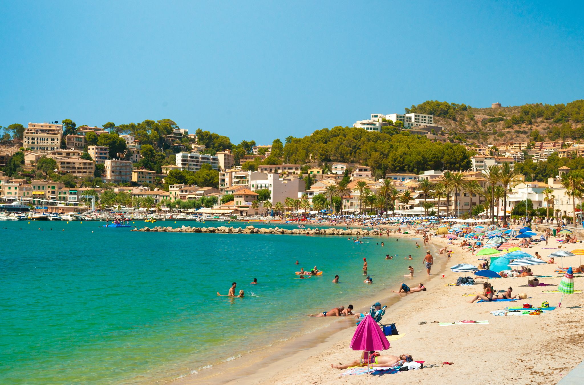 Colorful umbrellas on Puerto de Soller, Port of Mallorca island in balearic islands, Spain. Beautiful picture of people resting on the beach on bright summer day.