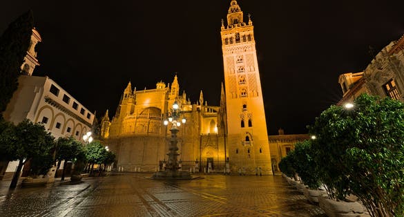 Photo of Seville Cathedral with Giralda Bell Tower, a former Moorish mosque , Spain .
