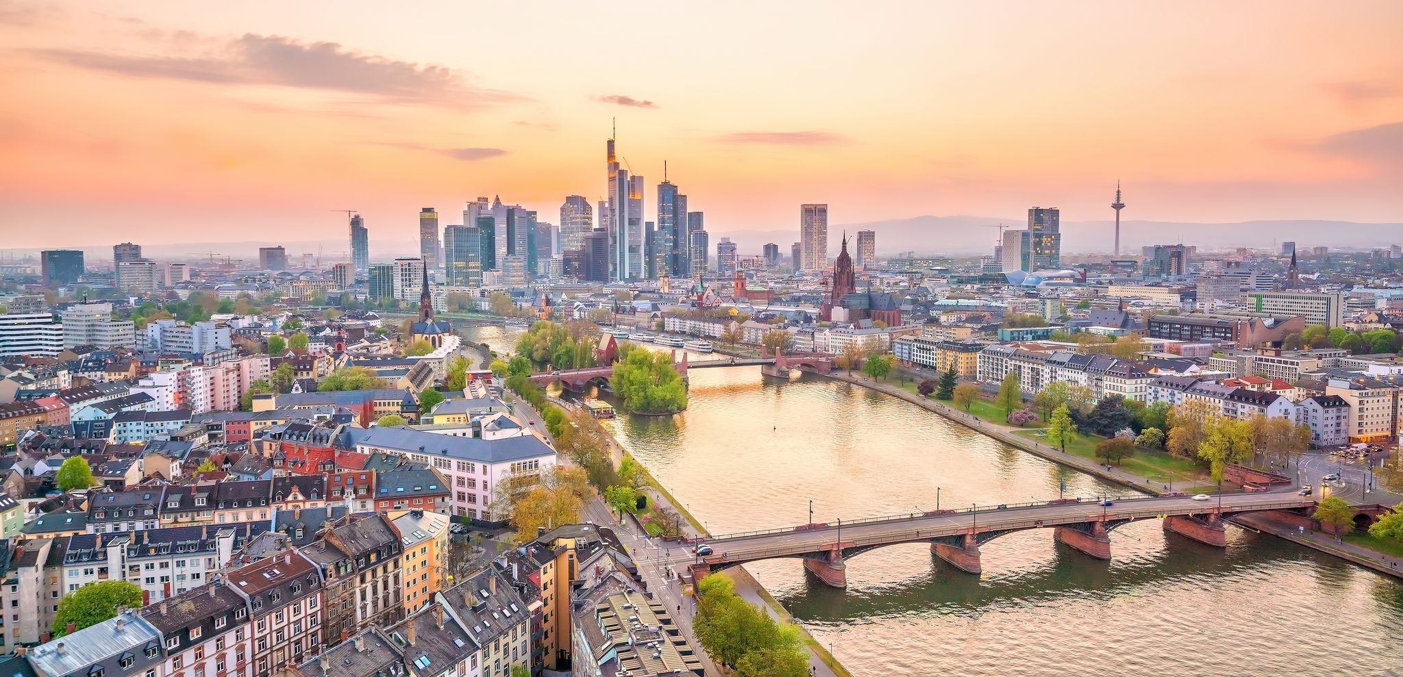 Cologne Aerial view with trains move on a bridge over the Rhine River on which cargo barges and passenger ships ply. Majestic Cologne Cathedral in the background.