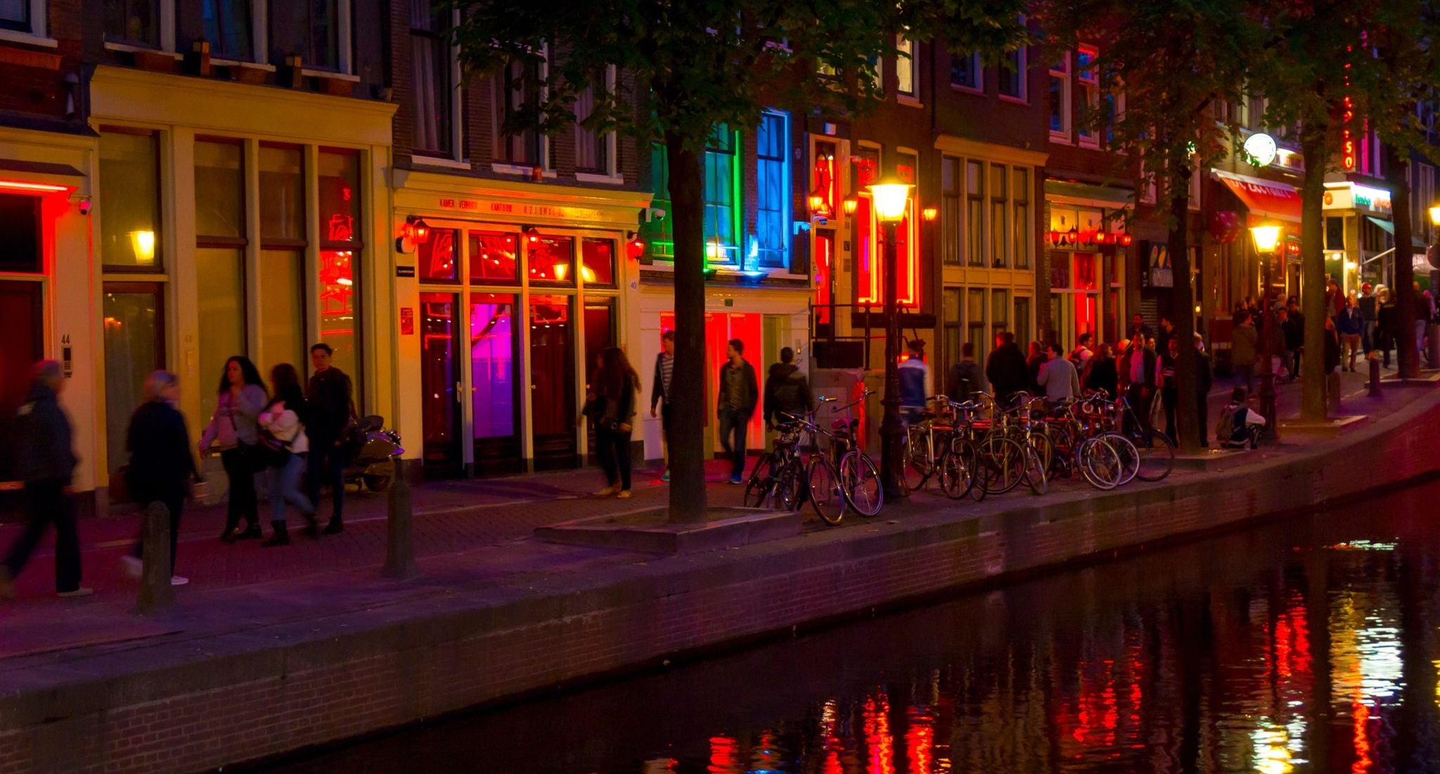 Night view of Amsterdam’s Red Light District with glowing windows and reflections on the canal..jpg