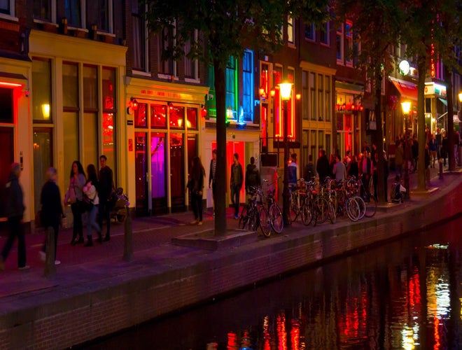 Night view of Amsterdam’s Red Light District with glowing windows and reflections on the canal..jpg