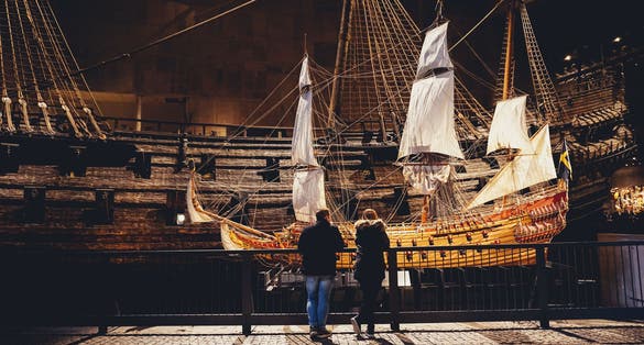People in front of model of Vasa, viking ship. The ship itself in the background