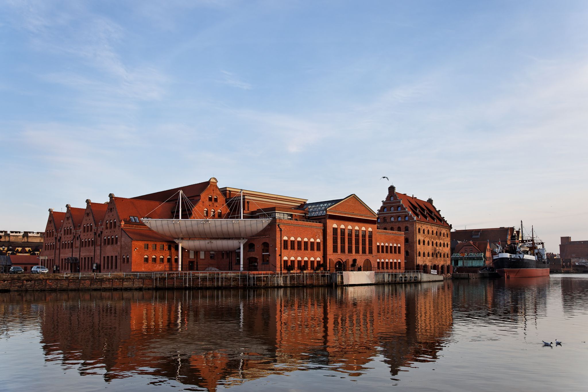 The historic building of the Baltic Philharmonic Orchestra with a ship in the background. Gdansk, Poland.