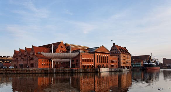 The historic building of the Baltic Philharmonic Orchestra with a ship in the background. Gdansk, Poland.