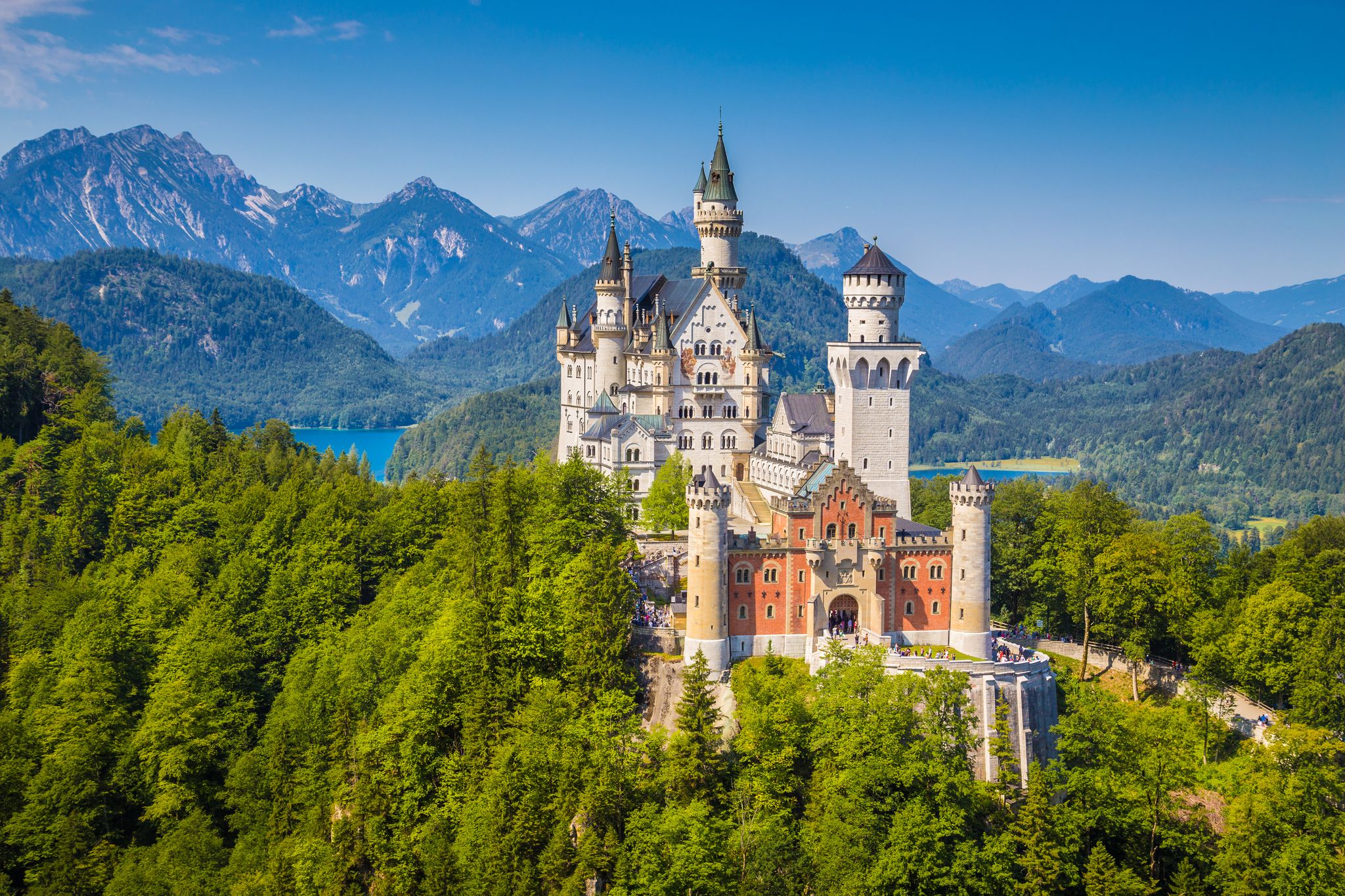 Photo of aerial beautiful view of world-famous Neuschwanstein Castle, the 19th century Romanesque Revival palace built for King Ludwig II, with scenic mountain landscape near Fussen, southwest Bavaria, Germany.