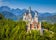 Photo of aerial beautiful view of world-famous Neuschwanstein Castle, the 19th century Romanesque Revival palace built for King Ludwig II, with scenic mountain landscape near Fussen, southwest Bavaria, Germany.