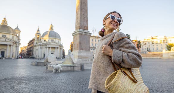 photo of woman walks on piazza del popolo in Rome city on a morning time. Female person with bag and colorful shawl in hair. Concept of italian lifestyle and travel.