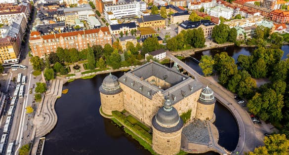photo of a drone shot of the beautiful Orebro Castle surrounded with Svartan river and the cityscape in Örebro County, Sweden.