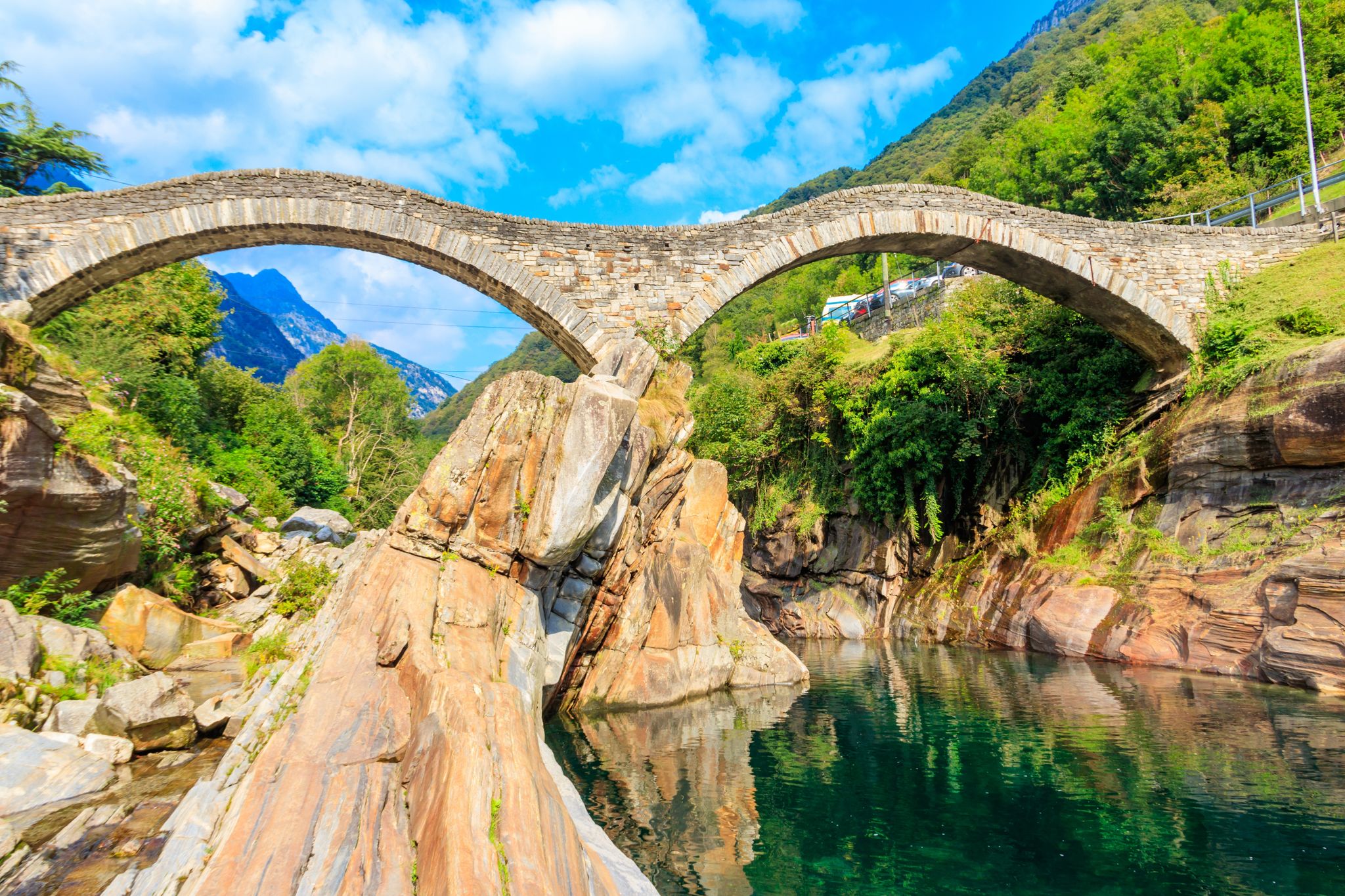 Photo of Ancient double arch stone Roman bridge (Ponte dei Salti) over the clear water of the Verzasca river in Lavertezzo ,Verzasca Valley, Ticino Canton, Switzerland.