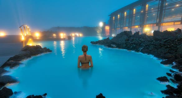 photo of woman enjoying natural spa blue lagoon in Western Iceland.