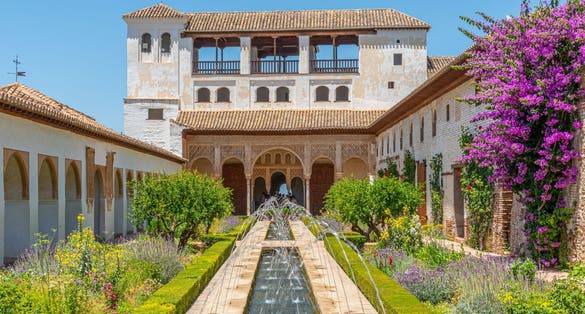 Photo of the Generalife courtyard, with its famous fountain and garden through an arch. Alhambra de Granada complex at Granada, Spain.