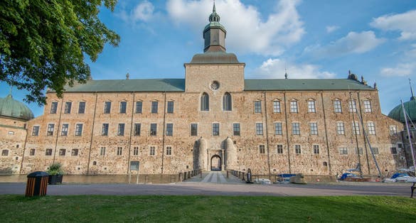 photo of Vadstena Castle and park in Sweden. View from outside the landmark. Entry to the inside by a bridge.