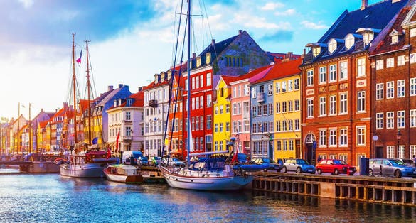 Photo of scenic summer sunset view of Nyhavn pier with color buildings, ships, yachts and other boats in the Old Town of Copenhagen, Denmark.