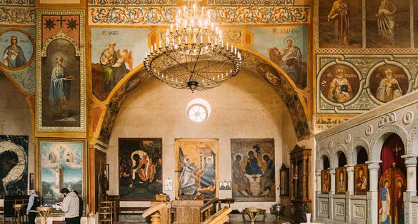 Photo of people praying in Shio-Mgvime Monastery. interior of Upper Church Of Holy Virgin Or Theotokos, Central Part Of Medieval Monastic.