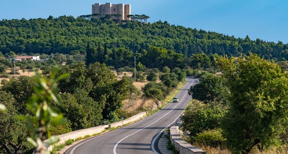 Scenic view of country road with Castel del Monte, the famous castle with its octagonal shape, in the background. Apulia, Italy.