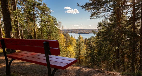 Photo of red bench and lake Pyhäjärvi in Tampere, Finland.