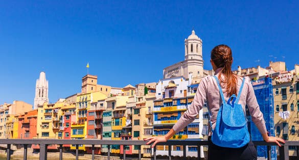 Photo of tourist woman looking on colorful houses and bridge river Onyar in Girona, Catalonia, Spain.