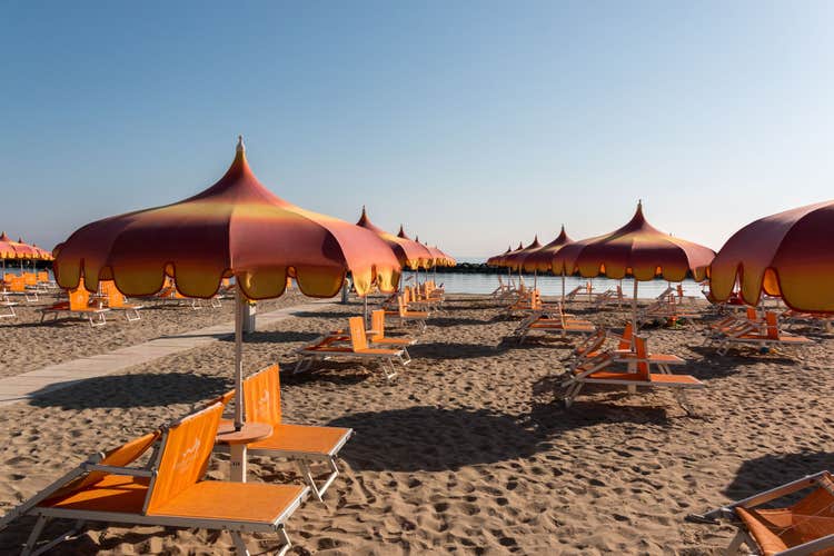 Photo of parasols and sunbeds on beautiful beach of Torre Pedrera in Italy.