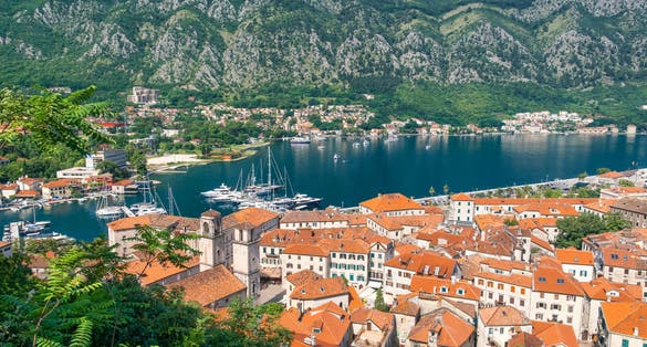 Photo of Aerial view of Kotor old town with orange rooftops and marina in Kotor bay with boats and yachts, Montenegro. Summer vacation resort on Adriatic fjord in summer day. Travel destination.