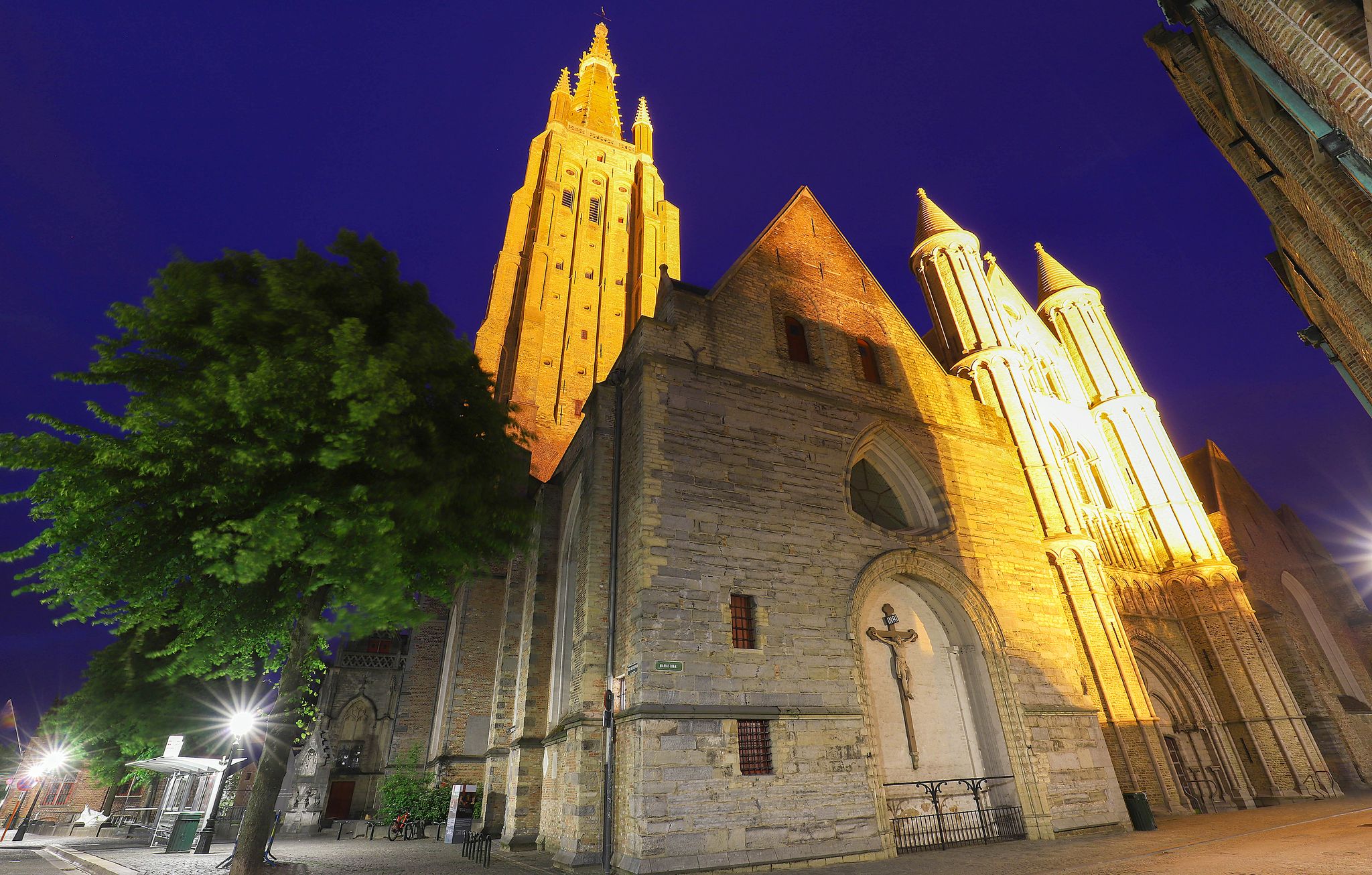 Photo of night view of a typical street of historic Bruges, with Onze-Lieve-Vrouwekerk-Church of Our Lady as background, Belgium.
