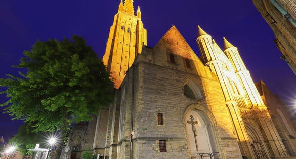 Photo of night view of a typical street of historic Bruges, with Onze-Lieve-Vrouwekerk-Church of Our Lady as background, Belgium.