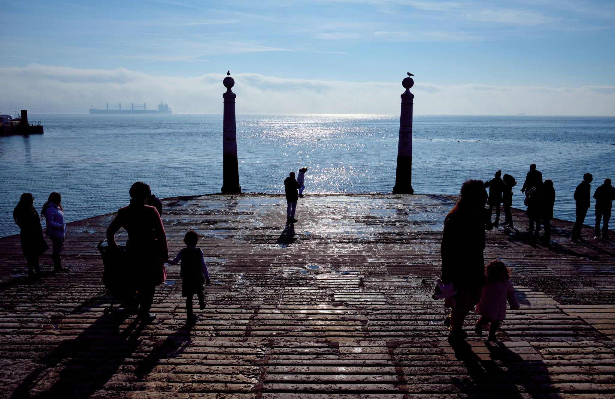 Tourists by the sea. Cais das Colunas in Lisbon, Portugal.