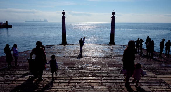 Tourists by the sea. Cais das Colunas in Lisbon, Portugal.