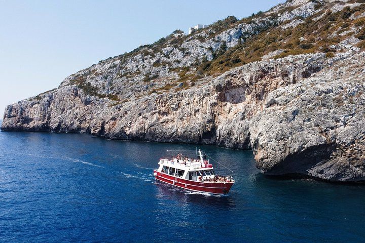 A tour boat is cruising near the rocky coast of Santa Maria di Leuca in southern Italy on a clear summer day..jpg