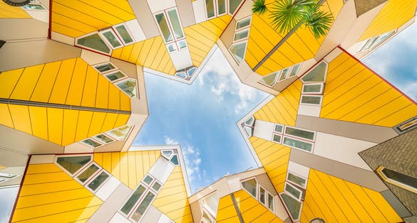 photo of star shapes formed where six Cube houses tilt into one another and intersect in Rotterdam, a quirky bright yellow architecturally unusual angular cube shape apartment block.