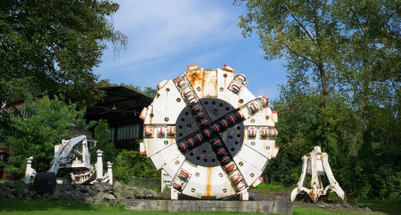 Photo of Miners and rock cutter combines are on the green grass in the Landek park, Ostrava, Czech Republic.