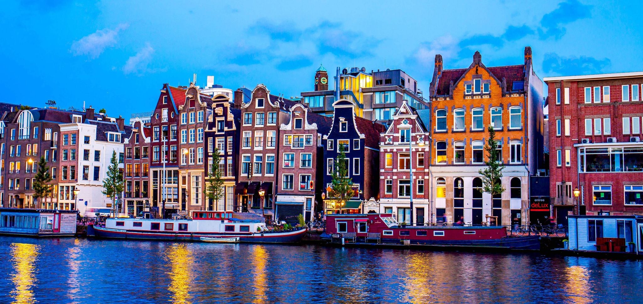 Traditional canal houses and boats reflecting on the water at dusk in Amsterdam..jpg