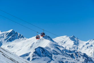 Two gondolas going up and down above the snow caped mountains. Gondolas are moving on thick ropes hanging very high. In the back there are tall Alps. Ski resort in Heiligenblut, Austria.