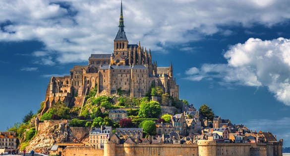 Photo of beautiful panoramic view of famous Le Mont Saint-Michel tidal island with blue sky, northern France.