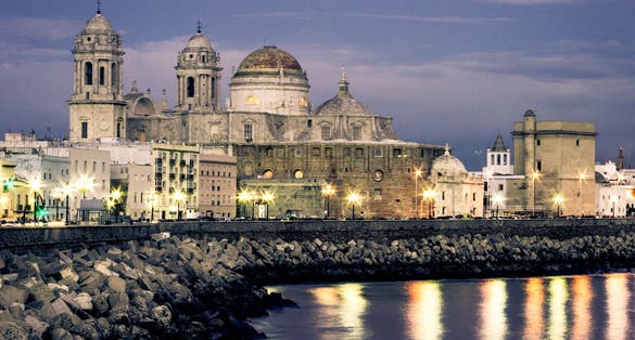 photo of beautiful view at night of the cathedral of Cadiz called cathedral de Santa Cruz with its 2 towers and its golden dome and ocean in Cadiz Andalusia Spain Europe.