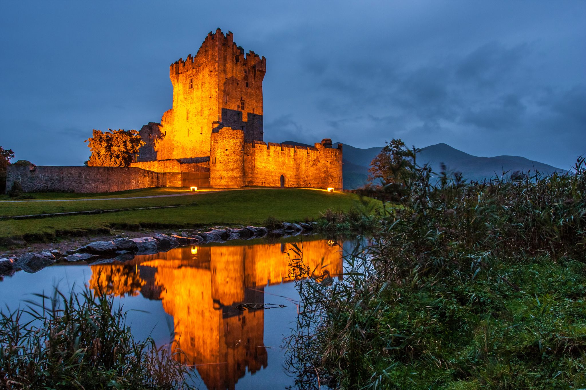 photo of view of Ross Castle illuminated at night in Killarney, Ireland.