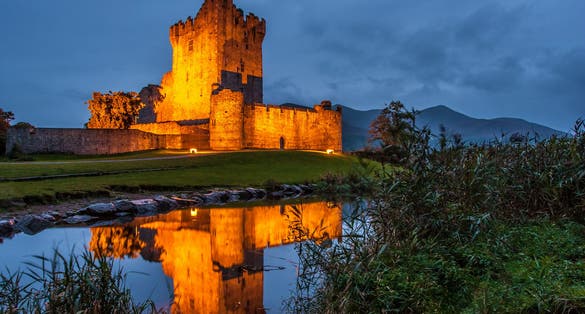 photo of view of Ross Castle illuminated at night in Killarney, Ireland.