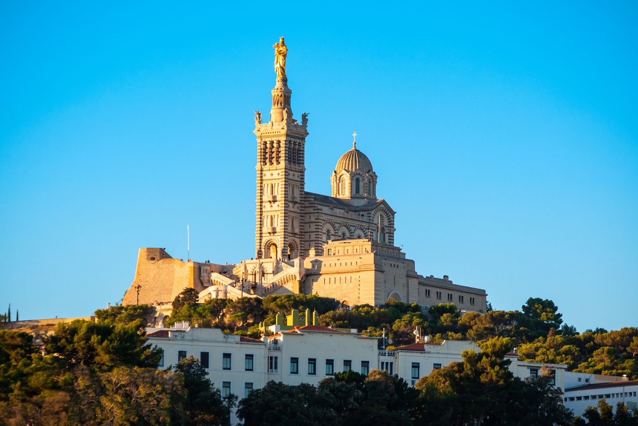 Notre-Dame de la Garde basilica in Marseille, France, perched on a hilltop and lit by golden afternoon sunlight..jpg