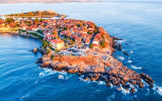 Photo of Saint Anastasia Island in Burgas bay, Black Sea, Bulgaria. Lighthouse tower and old wooden buildings on rocky coast.