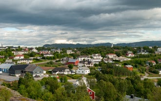 Photo of red houses facades reflecting on the bay of Alta, Norway.