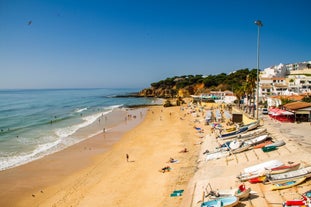 Photo of beautiful aerial view of the sandy beach surrounded by typical white houses in a sunny spring day, Carvoeiro, Lagoa, Algarve, Portugal.