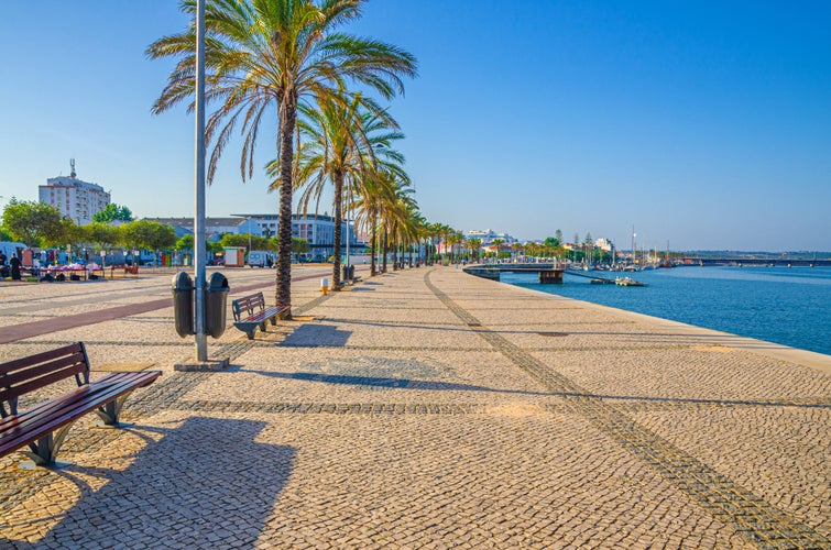 Photo of Ribeirinha de Portimao town, cobblestone embankment promenade of Arade River in city centre.